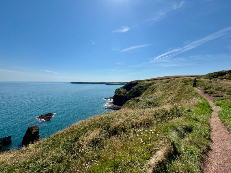 The trail following along the cliff overlooking the sea with rocks out in the water.