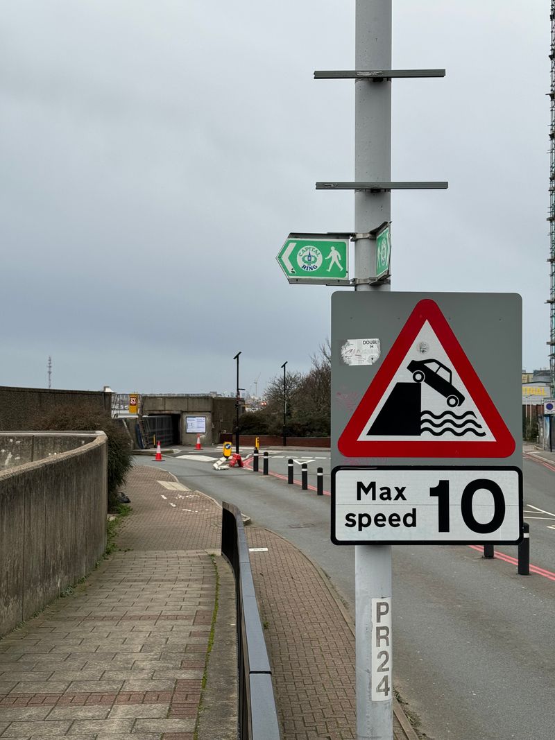 A road sign showing a car falling off a pier into the Thames