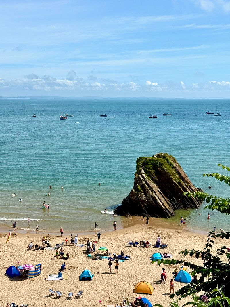 Looking down on the beach at Tenby. Just off the beach in the water a giant rocky crag is sticking out.