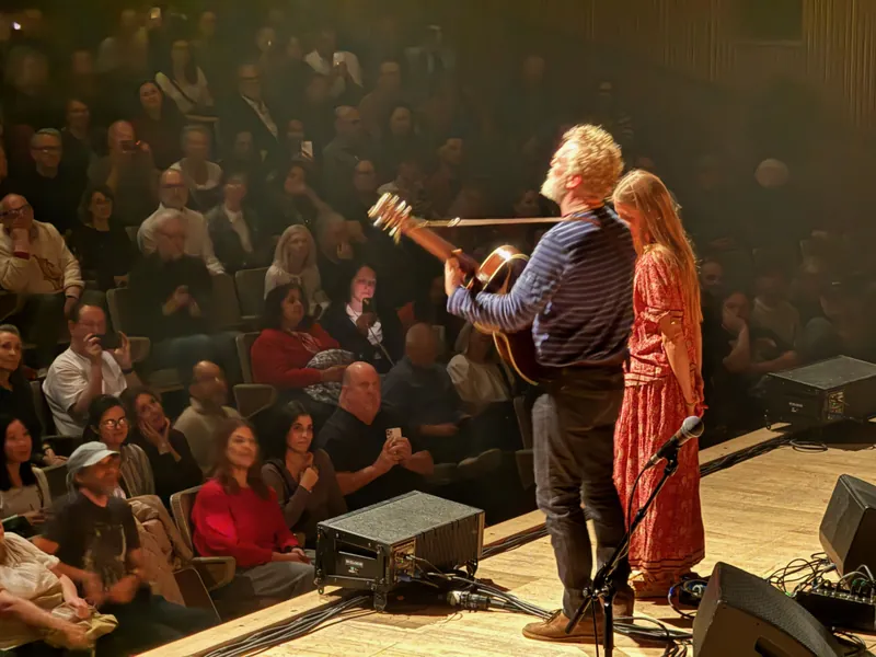 Glen and Markéta standing at the edge of the stage singing to the audience.
