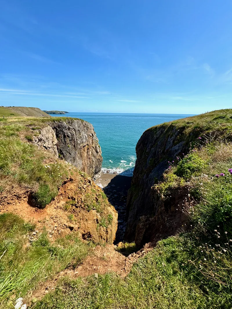A look down into a ravine. Steep cliffs on both sides and opening out onto the sea at the far end.
