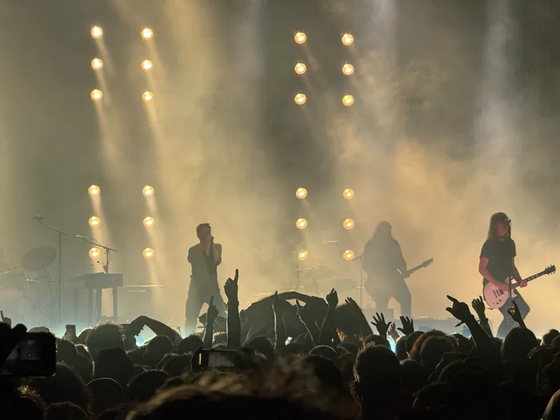 Trent and band backlit on the main stage. People are crowd surfing in front of him.