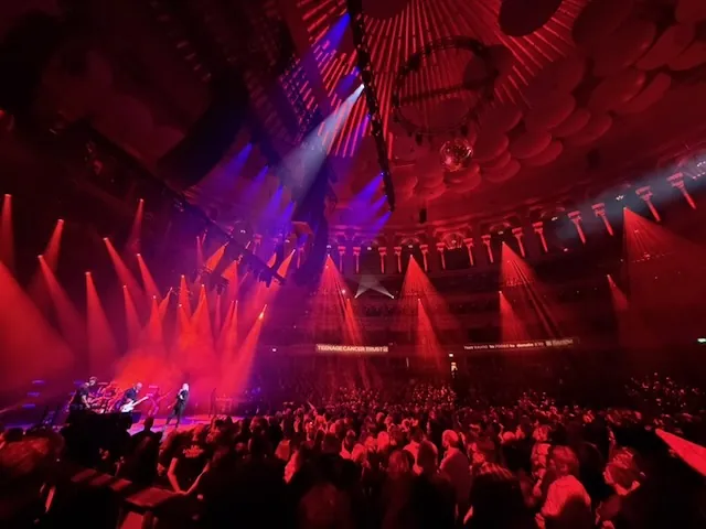 Wide-angle view of the Royal Albert Hall bathed in deep red and blue light during Garbage's set, with laser beams and a disco ball illuminating the crowd and ornate upper tiers.