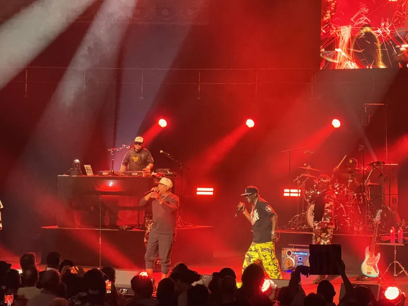 Close up shot of Chuck D and Flava Flav on stage with DJ Johnny Juce in the background