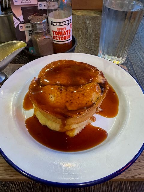 Classic British pie and mash on a white plate with gravy poured over it