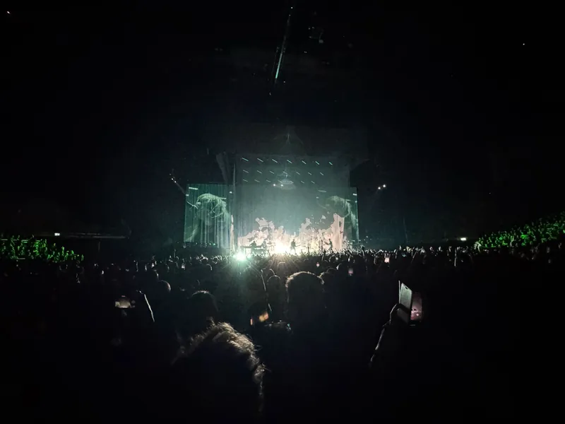 A wide shot of the arena with light and smoke pouring off the stage