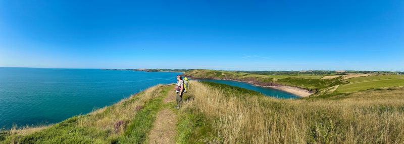 A wide angle view is the sea on the left. Straight ahead the trail leads down and to the right into a beach off in the distance